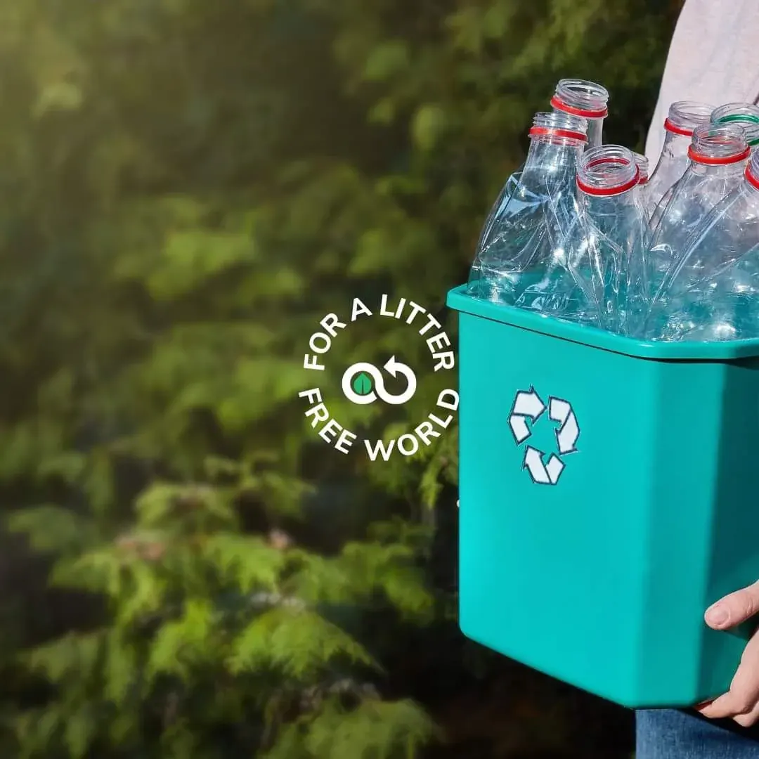 Person holding a recycling bin filled with plastic bottles during a community recycling challenge