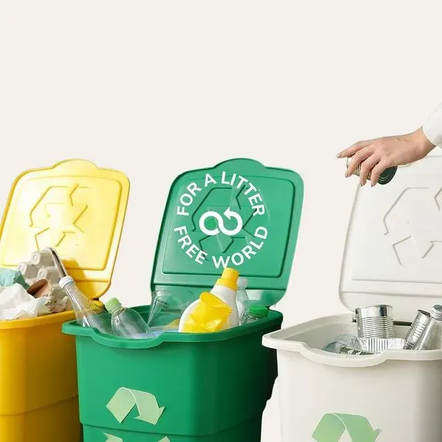 Hand placing items into household recycling bins with plastic bottles and cans, supporting local bottle recycling in the UAE